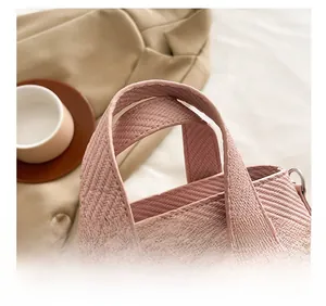 Close-up of pink woven handbag featuring reinforced wide handles and textured twill pattern