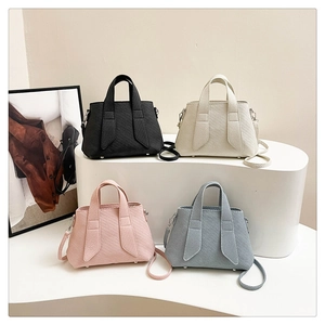 Close-up of textured bucket bag featuring wide handles and protective metal feet studs