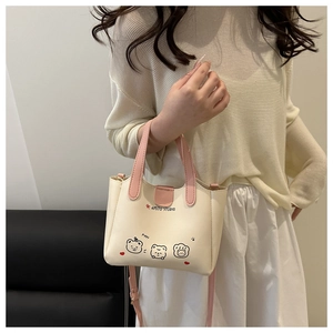 Détail du sac à main en cuir PU crème avec imprimés d'ours et poignée rose