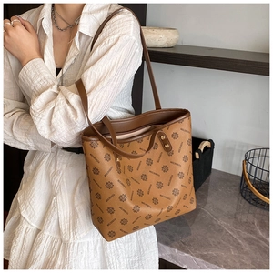 Brown vintage tote bag with patterned prints shown as a shoulder bag on a model