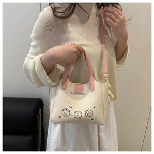 Détail d'un sac cabas crème avec imprimé ours mignon et poignées roses élégantes