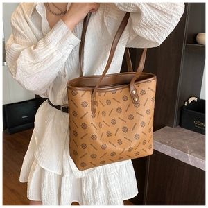 Detail of vintage brown monogram tote bag with leather straps and gold rivets