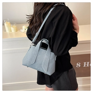 Detail of light blue striped tote bag with adjustable strap and metal bottom studs
