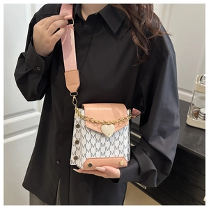 Detalle de mini bolso bandolera con colgante de corazón y correa rosa sobre ropa negra