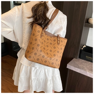 Brown tote bag with vintage print shown on shoulder with a white textured dress