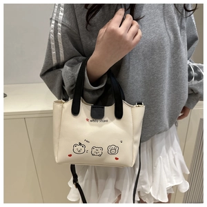 Détail d'un sac seau beige avec imprimés de dessins animés et anses noires contrastées