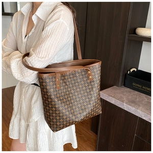 Close-up of brown textured leather tote bag with metallic rivets and shoulder strap detail