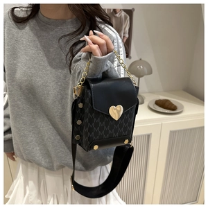 Detalle de bolso bandolera con costuras en contraste, hebilla de corazón y correa ancha