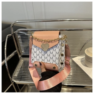 Detail of contrast color square bag with heart lock and chain handle on display stand