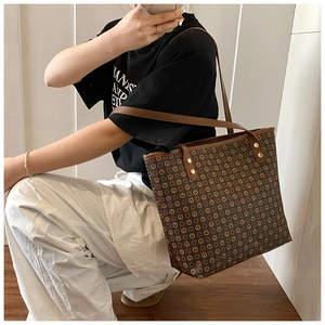 Detail of vintage tote bag featuring brown leather straps and gold metal rivet reinforcements