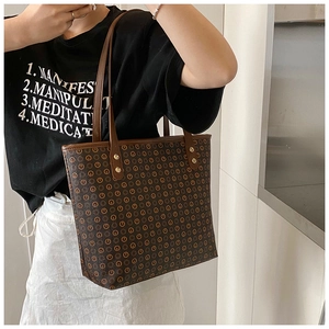Detail view of brown monogram tote bag with sturdy straps and vintage pattern texture