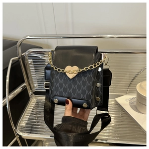 Detail of crossbody bag featuring heart-shaped gold buckle and logo print fabric