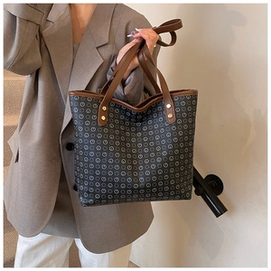 Deep grey tote bag with monogram print and brown leather trim shown on model