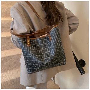 Rear view of a vintage tote bag with pattern and metal rivet details on model