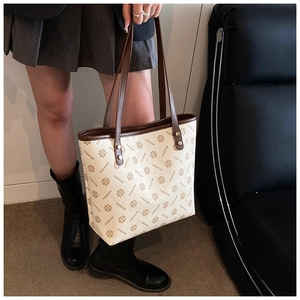 Detail of vintage beige floral tote bag with brown leather handles and brand pattern