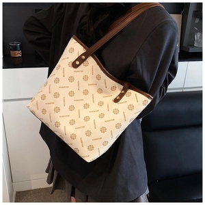 Detail of vintage beige tote bag with clover print and brown leather straps on model