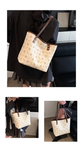 Detail view of large retro tote bag with monogram pattern and brown leather straps