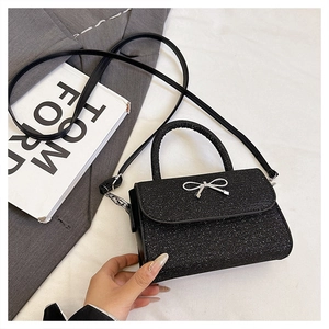 Detail of black sequin crossbody bag featuring a silver bow buckle and top handle