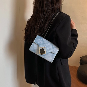 Blue denim texture crossbody chain bag with golden metal buckle worn by a model
