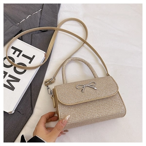 Detail of champagne gold woven small square bag with silver metal bow and top handle