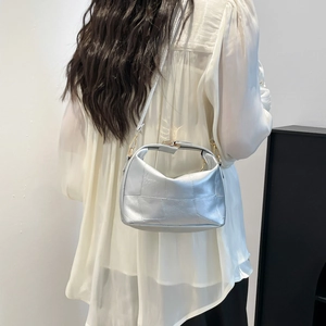 Silver metallic patchwork crossbody bag with slim strap shown on shoulder in a minimalist style