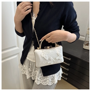 Detailed view of white mini handbag with 3D butterfly embroidery and gold handle