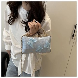 Detail of 3D butterfly embroidery on elegant light blue silk fabric with a gold handle