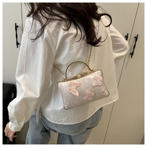 Detail of white jacquard mini bag featuring pink butterfly embroidery and metal handle