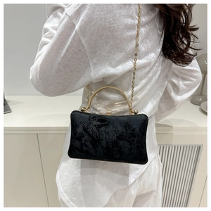 Close-up of black jacquard wedding bag with butterfly embroidery and gold metal handle