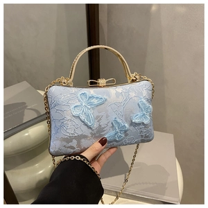 Close-up of light blue lace evening bag with 3D butterfly embroidery and gold metal handle