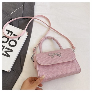 Close-up of pink glitter small handbag featuring a silver metal bow and slim shoulder strap