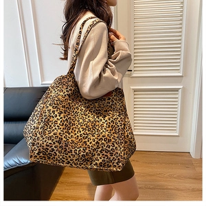Détail d'un grand sac cabas en toile à imprimé léopard porté sur l'épaule