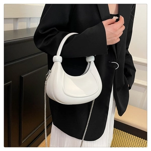 Minimalist white crescent moon bag styled with a sleek metal chain on a female model