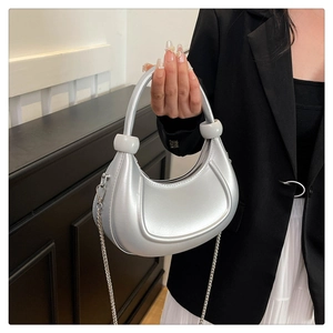 Detail of silver crescent hobo bag with metallic finish and sphere handle hardware