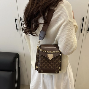 Brown crossbody bag with M-letter print and golden heart buckle shown on model