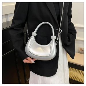 Silver crescent underarm bag with metal chain strap shown with a model outfit