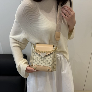 Chic cream crossbody bag with M-pattern print, gold chain, and wide shoulder strap