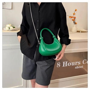 Detailed view of an emerald green crescent bag with integrated ring handle and silver chain