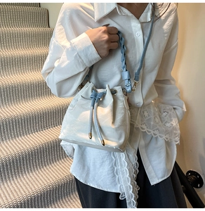Detail of white and blue colorblock bucket bag with woven handle and drawstring