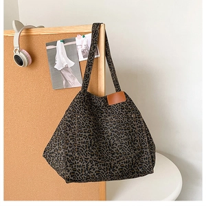 Gros plan du sac cabas léopard en toile avec poche à rivets et détail d'étiquette en cuir