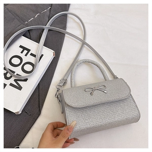Detail of silver glitter handbag with bow accent and chain strap on fashion books