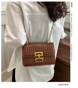 Détail d'un sac bandoulière matelassé marron avec boucle dorée et bandoulière chaîne