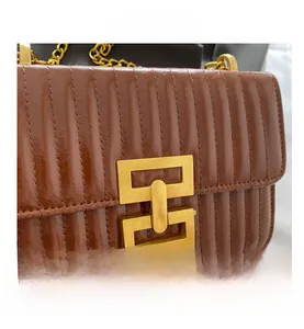 Détail du sac bandoulière matelassé marron avec une grande boucle géométrique dorée