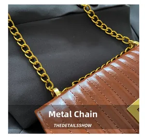 Détail de la chaîne dorée et des coutures sur le sac plissé en cuir marron brillant