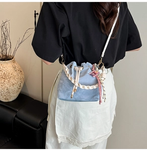 Rear view of a model wearing a light blue drawstring bucket bag with woven handle details
