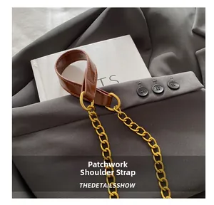 Détail d'une bandoulière en cuir marron avec chaîne en métal doré sur fond gris foncé