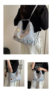 Detail of silver pleated backpack featuring colorful heart patches and slim straps