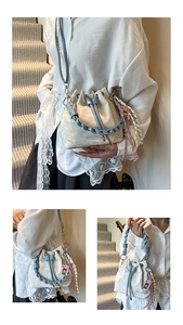 Detail of cream drawstring bucket bag with light blue woven handle and metal hardware