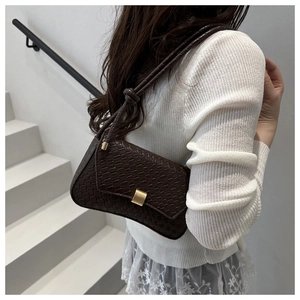Detail of dark brown quilted shoulder bag with gold clasp and textured PU leather
