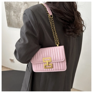 Pink quilted shoulder bag with gold chain strap shown on a model in a minimalist style